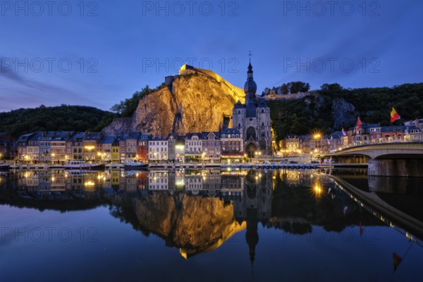 Night view of Dinant town, Collegiate Church of Notre Dame de Dinant over River Meuse and Pont Charles de Gaulle bridge and Dinant Citadel illuminated in the evening. Dinant, Belgium, Europe