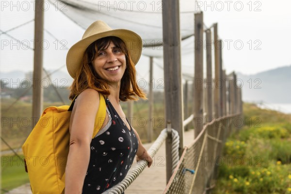 Summer vacation lifestyle. Young and adventurous Caucasian girl smiling with a hat enjoying the summer looking at the sea on the beach