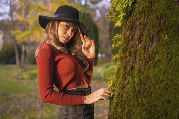 Lifestyle, portrait of a caucasian girl in a black hat at sunset in a green park