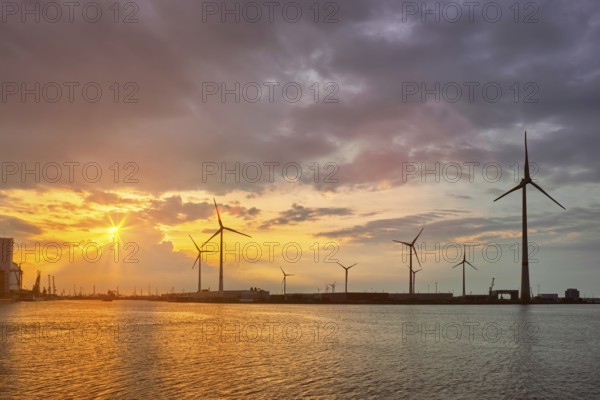 Wind turbines power electricity generators in Antwerp port on sunset. Antwerp, Belgium, Europe