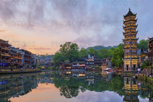 Chinese tourist attraction destination, Feng Huang Ancient Town (Phoenix Ancient Town) on Tuo Jiang River with Wanming Pagoda illuminated at night. Hunan Province, China, Asia