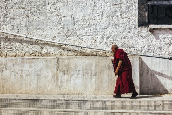 SPITUK, INDIA, SEPTEMBER 15, 2012: Old buddhist monk walking along the wall of Spituk gompa, Ladakh, India, Asia