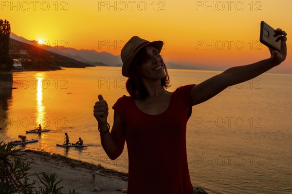 Silhouette of a woman taking a selfie at sunset at Shkoder lake in Shiroka municipality, summer vacation. Albania