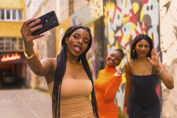 San Sebastián, Gipuzkoa Spain, February 2021: Three girls taking a selfie. Fashionable urban style with three black African girls on a city street, tight dresses