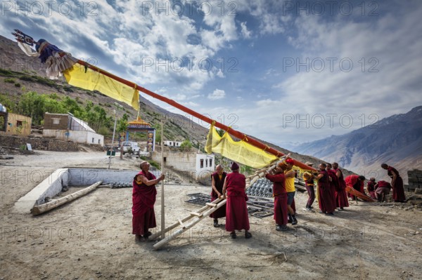 DHANKAR, INDIA, JULY 2, 2012: Tibetan Buddhist monks of Dhankar gompa setting up the pole with prayer flags. Dhankar, Spiti valley, Himachal Pradesh, India, Asia