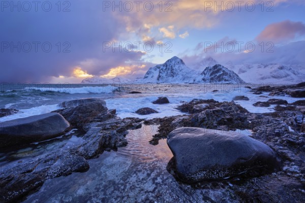 Beach of Norwegian sea on rocky coast in fjord on sunset in winter. Vareid beach, Lofoten islands, Norway, Europe
