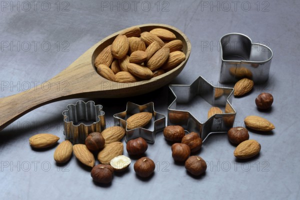Wooden ladle with almonds and hazelnuts, cookie cutters, baking ingredient