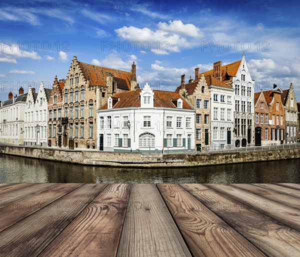 Wooden planks with European view of Bruges canal and old historic houses of medieval architecture in background. Brugge, Belgium, Europe