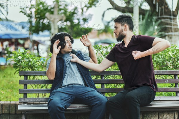 Two male friends arguing on a park bench. Two guys arguing sitting on a bench