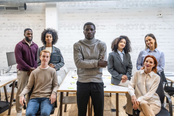 Portrait of an african man standing next to coworking colleagues sitting around a table