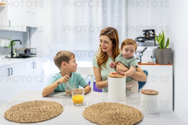 Mother with baby having breakfast with schoolboy at home before going to school
