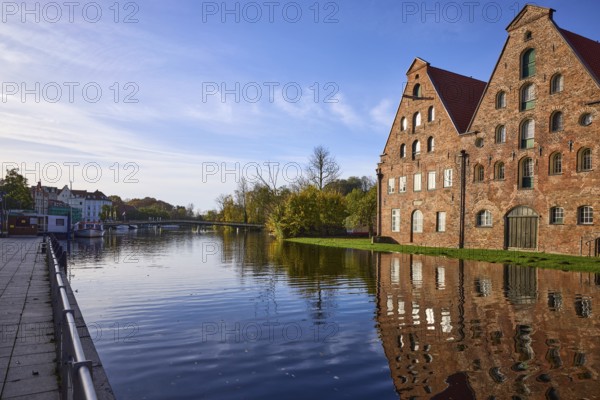 Historic salt warehouses with reflections on the water surface, morning light, Liebesbrücke, Hanseatic City of Lübeck, Schleswig-Holstein, Germany, Europe