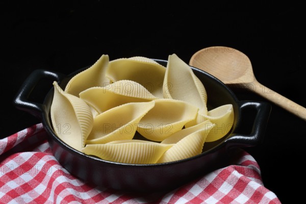 Conchiglione, Italian pasta in pot with cooking spoon