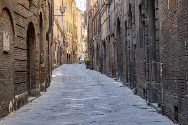 View of a small street going through old buildings in the city of Siena, Tuscany, Italy, Europe