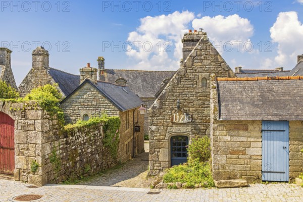 Alley in an old idyllic french villages with picturesque stone houses with lush green garden plants, Locronan, Bretagne, France, Europe