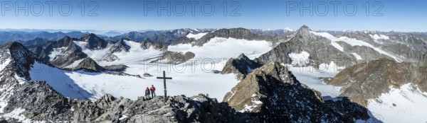 Panorama at the summit of the Wilder Freiger with summit cross and with glacier Übeltalferner and Wilder Freiger Ferner, two mountaineers at the summit in front of a spectacular mountain landscape, aerial view, Stubai Alps, South Tyrol, Italy, Europe