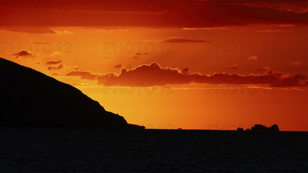 Dramatic sunset over the sea with a silhouetted island and a bright orange sky, sunset, Kassos, Karpathos, offshore islands, Dodecanese, Greek Islands, Greece, Europe