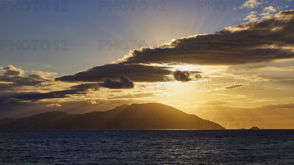 A sunset with rays bathing the sea and an island in a golden hue, sunset, Kassos, Karpathos, offshore islands, Dodecanese, Greek Islands, Greece, Europe
