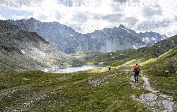 Mountaineers on a hiking trail, rocky mountain peaks of the Panargenkamm and Neue Reichenberger Hütte with mountain lake Bödensee, Lasörlinggruppe, Hohe Tauern National Park, East Tyrol, Austria, Europe