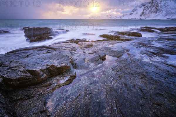 Beach of Norwegian sea on rocky coast in fjord on sunset in winter. Vareid beach, Lofoten islands, Norway, Europe