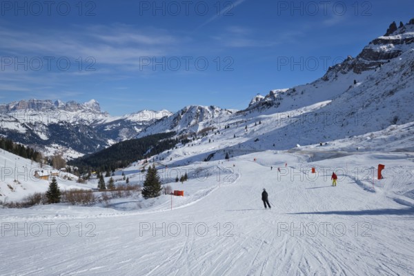 View of a ski resort piste with people skiing in Dolomites in Italy. Canazei, Italy, Europe
