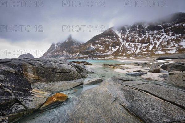 Rocky coast of fjord of Norwegian sea in winter with snow. Haukland beach, Lofoten islands, Norway, Europe