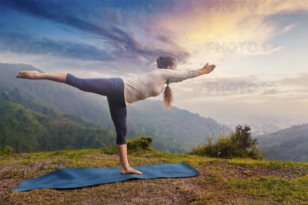 Yoga outdoors, sporty fit woman doing Ashtanga Vinyasa Yoga asana Virabhadrasana 3 Warrior pose posture in mountains