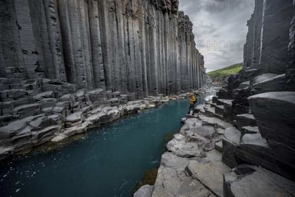 Tourist standing by the river in Stuðlagil Canyon, turquoise blue river between basalt columns, Egilsstadir, Iceland, Europe
