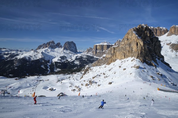 View of a ski resort piste with people skiing in Dolomites in Italy. Ski area Belvedere. Canazei, Italy, Europe