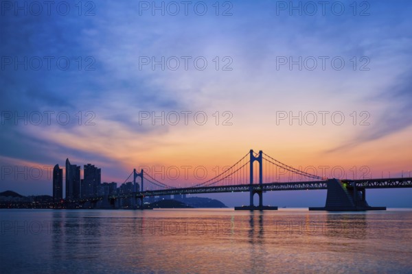 Gwangan Bridge on sunrise with skyscrapers and dramatic sky. Busan, South Korea, Asia