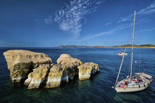Sarakiniko, Greece, May 23, 2019: Yacht boat with tourists passing near white rocks of famous tourist attraction of Milos island Sarakiniko beach Milos island, Greece, Europe