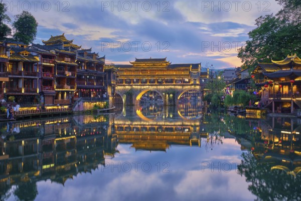 Chinese tourist attraction destination, Feng Huang Ancient Town (Phoenix Ancient Town) on Tuo Jiang River illuminated at night. Hunan Province, China, Asia