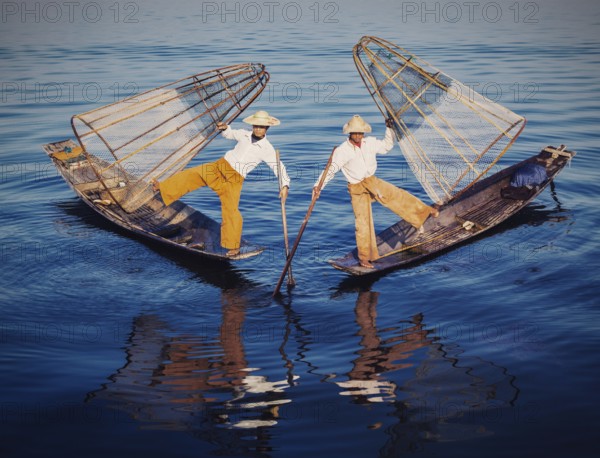 Myanmar travel attraction, Traditional Burmese fishermen balancing with fishing nets at Inle lake in Myanmar. Vintage filtered retro effect hipster style image
