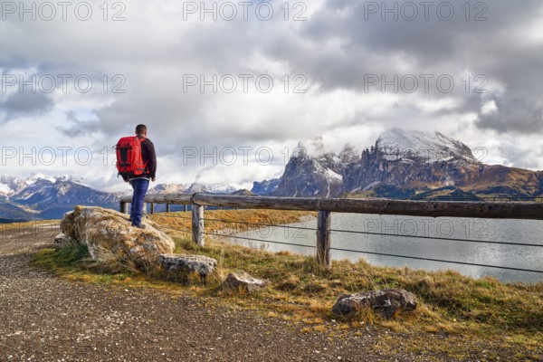 Hiker standing on stone, Sassopiatto, Sassolungo, Dolomites, Alpe di Siusi, lake, snow, clouds, Castelrotto, South Tyrol