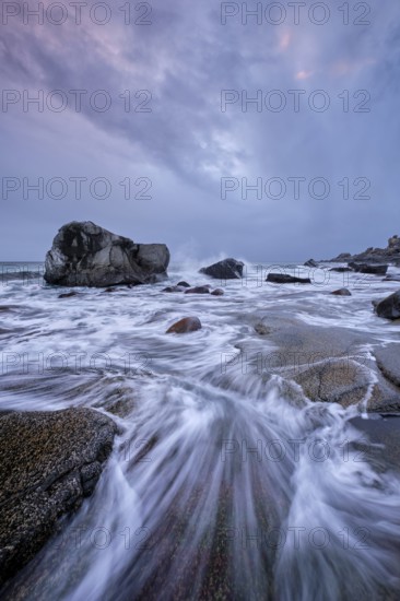 Rocks on beach of fjord of Norwegian sea in winteron sunset. Utakliev beach, Lofoten islands, Norway, Europe
