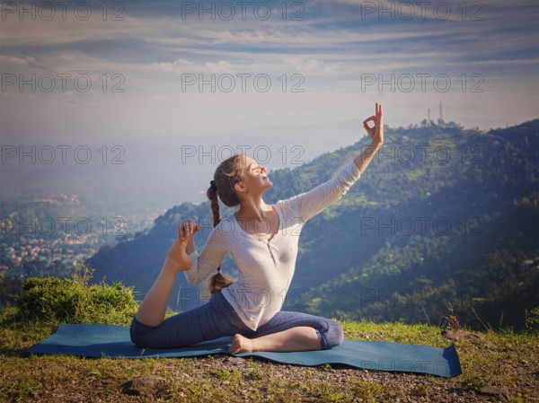 Yoga outdoors, young sporty fit woman doing stretching yoga asana Eka pada rajakapotasana, one-legged king pigeon pose in Himalayas mountains, India. Vintage retro effect filtered hipster style image