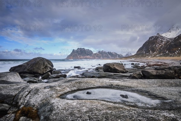 Rocks on beach of fjord of Norwegian sea in winter with snow. Utakliev beach, Lofoten islands, Norway, Europe