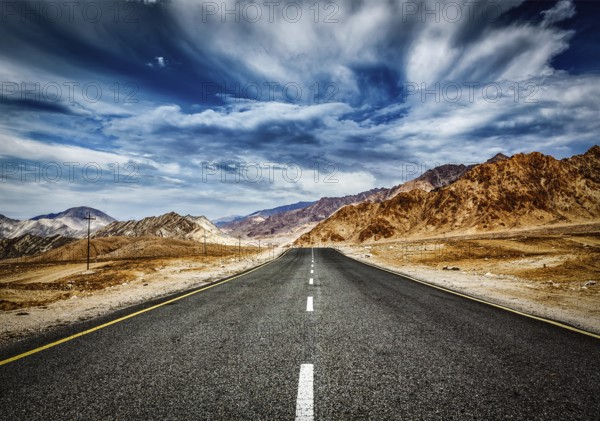 Travel forward concept background, road in Himalayas mountains and dramatic clouds. Ladakh, Jammu and Kashmir, India, Asia