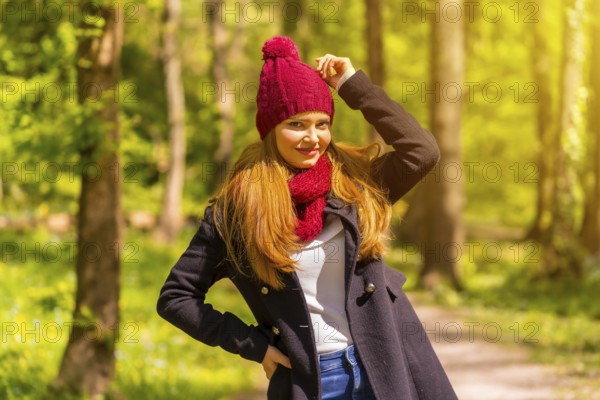 Latin girl with a black jacket, scarf and red woolen hat enjoying in an autumn park, smiling looking at camera
