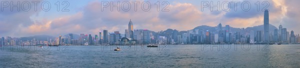 HONG KONG, CHINA, APRIL 28, 2018: Hong Kong skyline cityscape downtown skyscrapers over Victoria Harbour in the evening on sunset with junk tourist boat ferries, Hong Kong, China, Asia