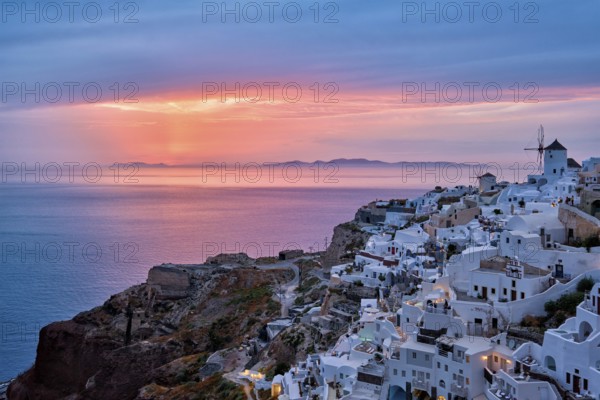 Famous greek iconic selfie spot tourist destination Oia village with traditional white houses and windmills in Santorini island on sunset in twilight, Greece, Europe