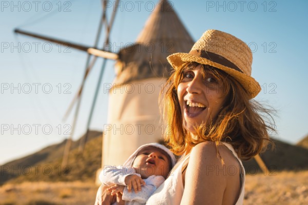 Happy woman with newborn visiting old windmills in Cabo de Gata, Spain, Europe