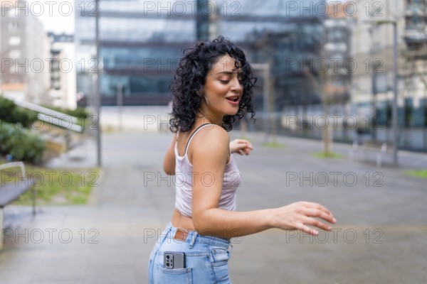 Carefree young woman dancing joyfully in an urban setting, embracing the rhythm of music and celebrating her vibrant spirit