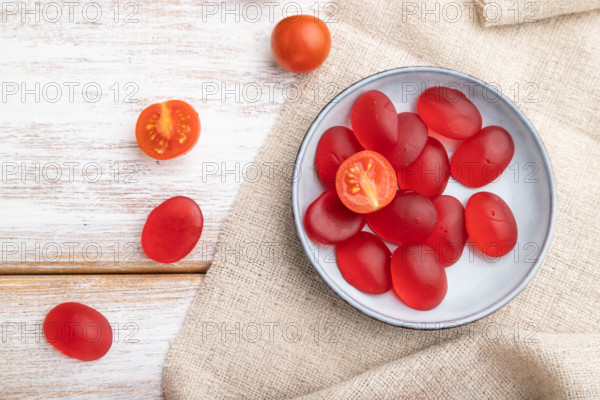 Jelly tomato candies on white wooden background and linen textile. close up, top view, flat lay