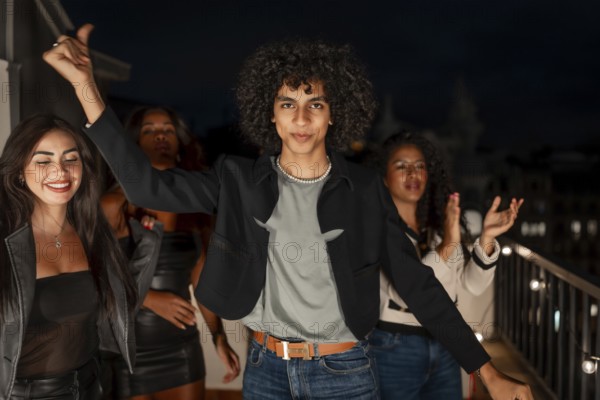 Man looking at camera dancing next to multi-ethnic friends in a terrace at night