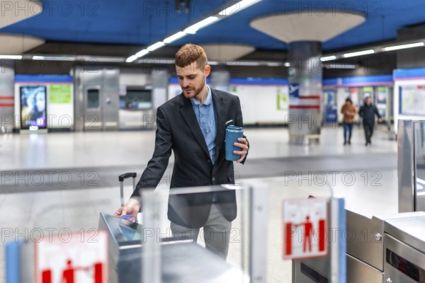 Businessman holding reusable coffee cup and using contactless credit card to enter subway station