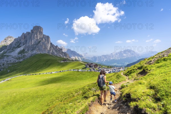 Mother and son hiking on a sunny day in the italian dolomites at giau pass, enjoying the breathtaking view