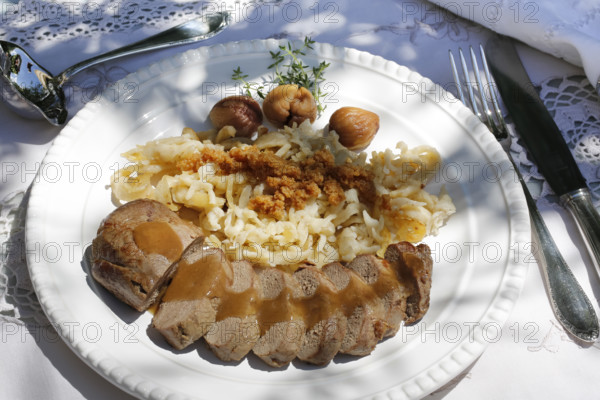 Swabian cuisine, roast venison with spaetzle, chestnuts and breadcrumbs, breadcrumbs, saddle of venison arranged on a plate, gravy, game dish, meat, main course, gravy, cutlery, knife, fork, grandmother's kitchen, regional, home cooking, typical Swabian, traditional cuisine, festive tablecloth, food photography, studio, Germany, Europe