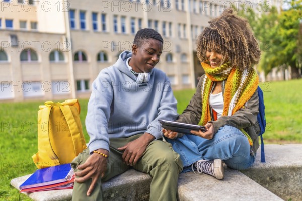 Multiethnic male and female college students sitting outdoors and using digital tablet together