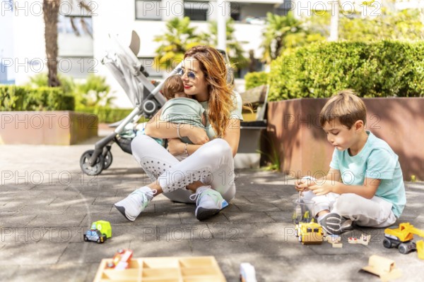 Mother embracing a baby while playing with his son in a park
